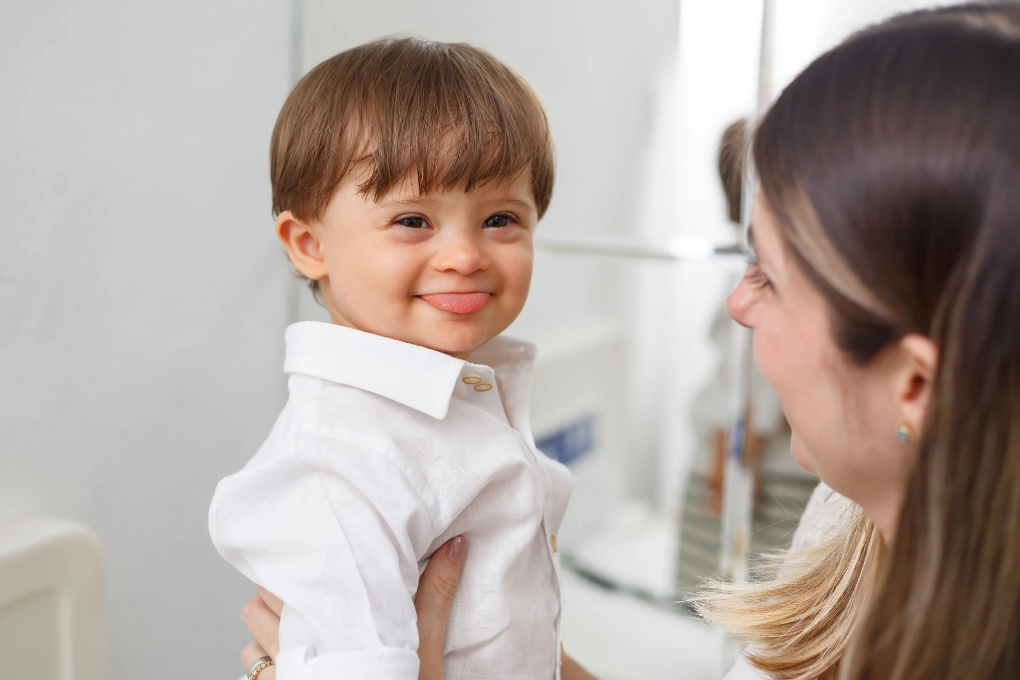 Smiling young child held by his mother at a birthday celebration.