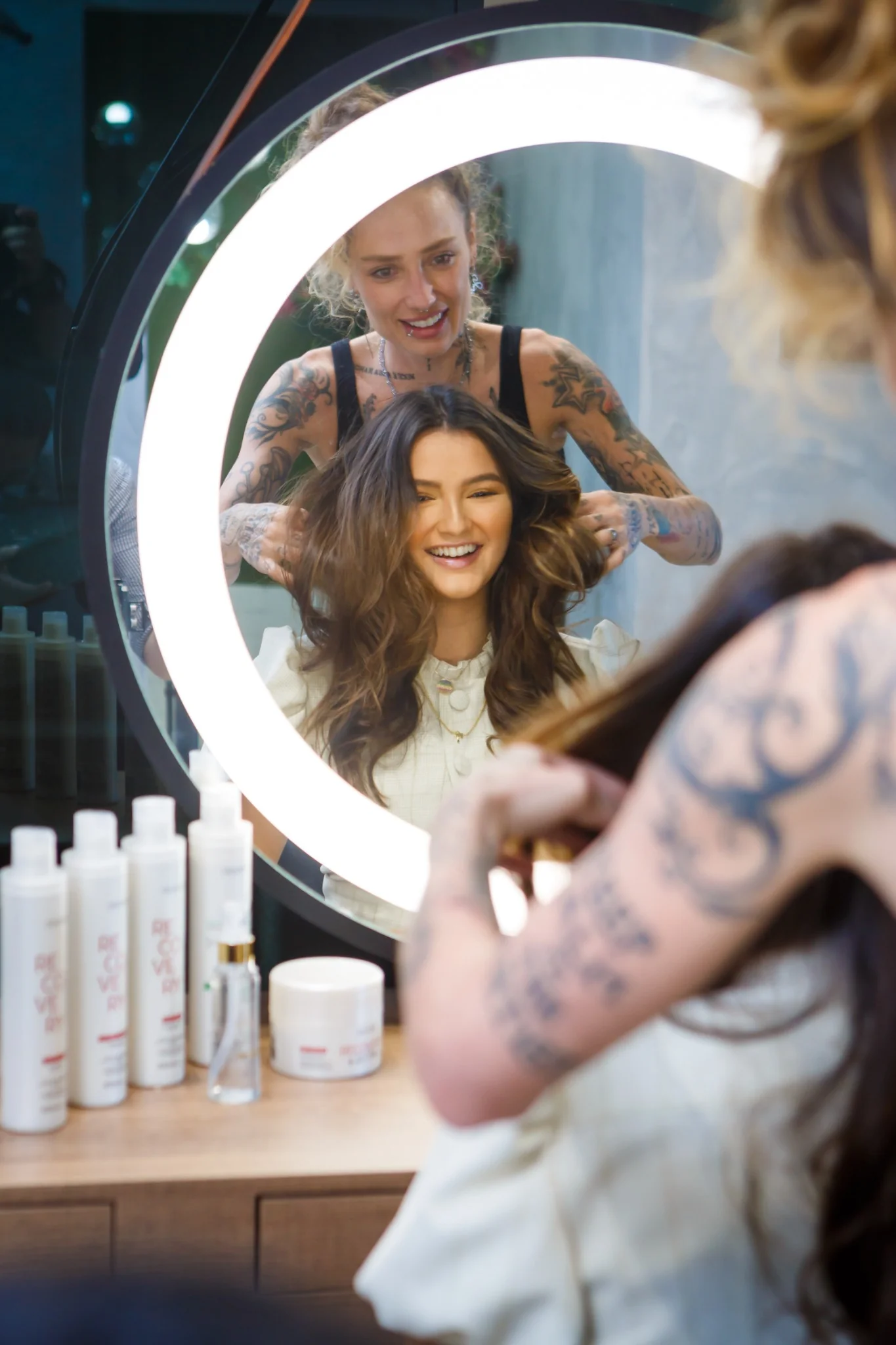 Hair stylist working with a seated woman in front of a mirror at a Chanté brand production.