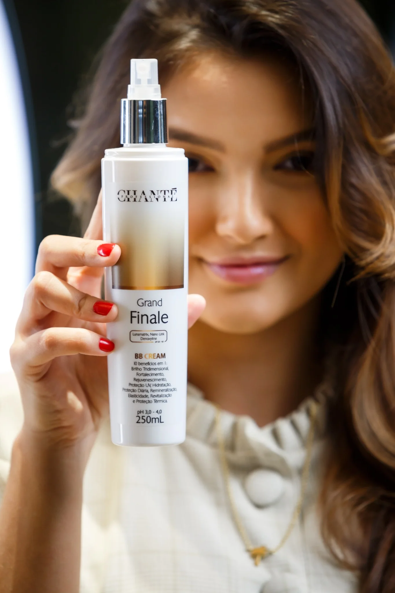 Close portrait of a woman holding a Chanté hair product beside her face.