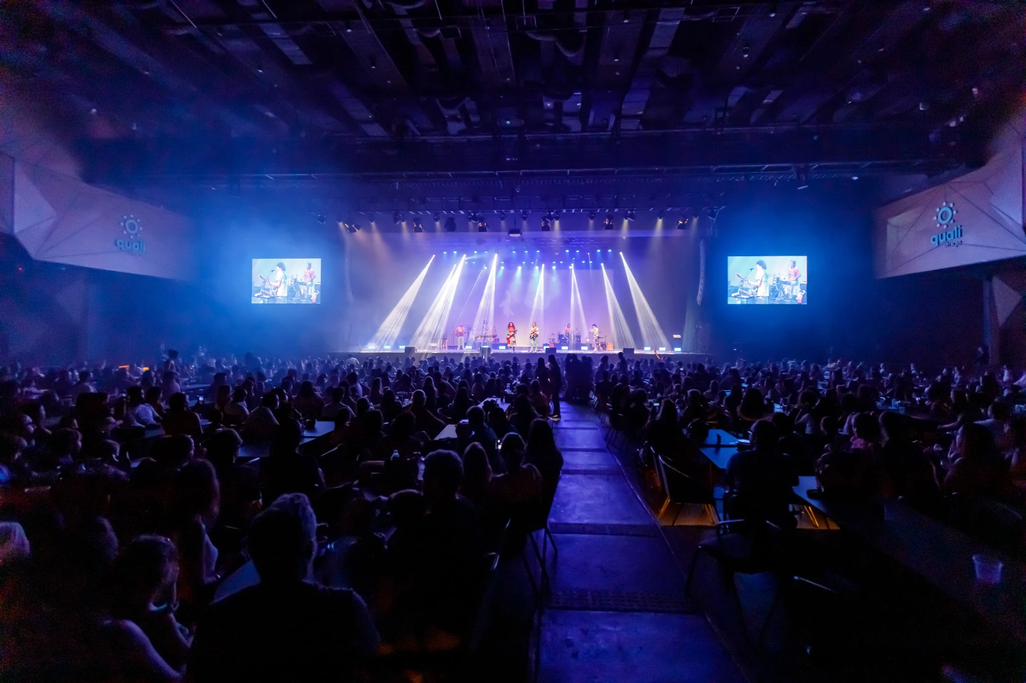 Illuminated stage and audience at a Palavra Cantada concert.