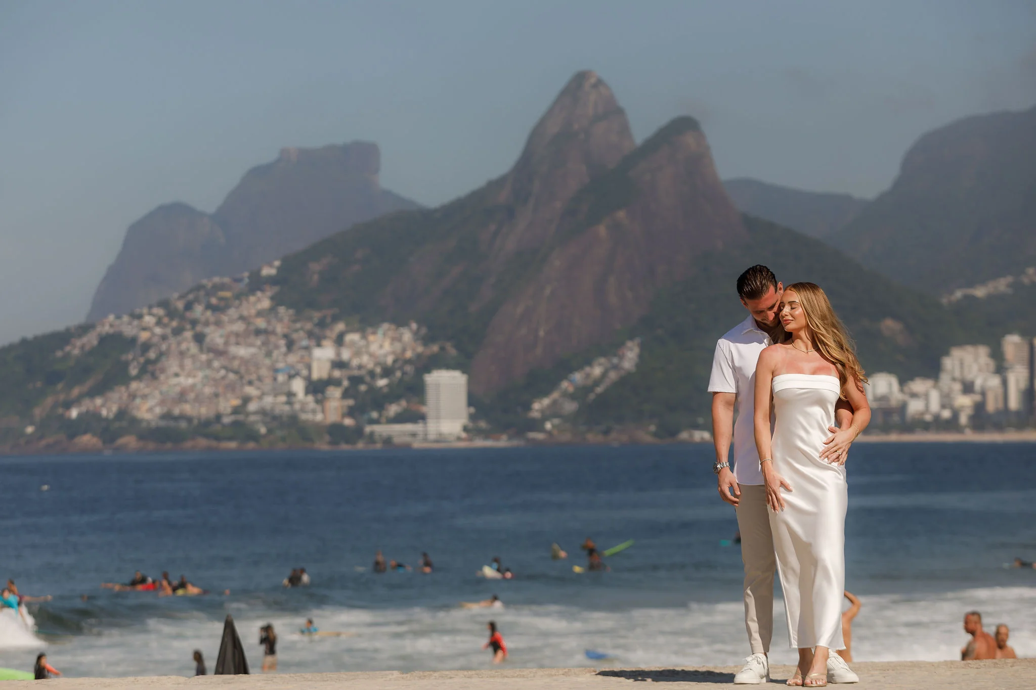 Couple embracing at Arpoador with Rio de Janeiro in the background.