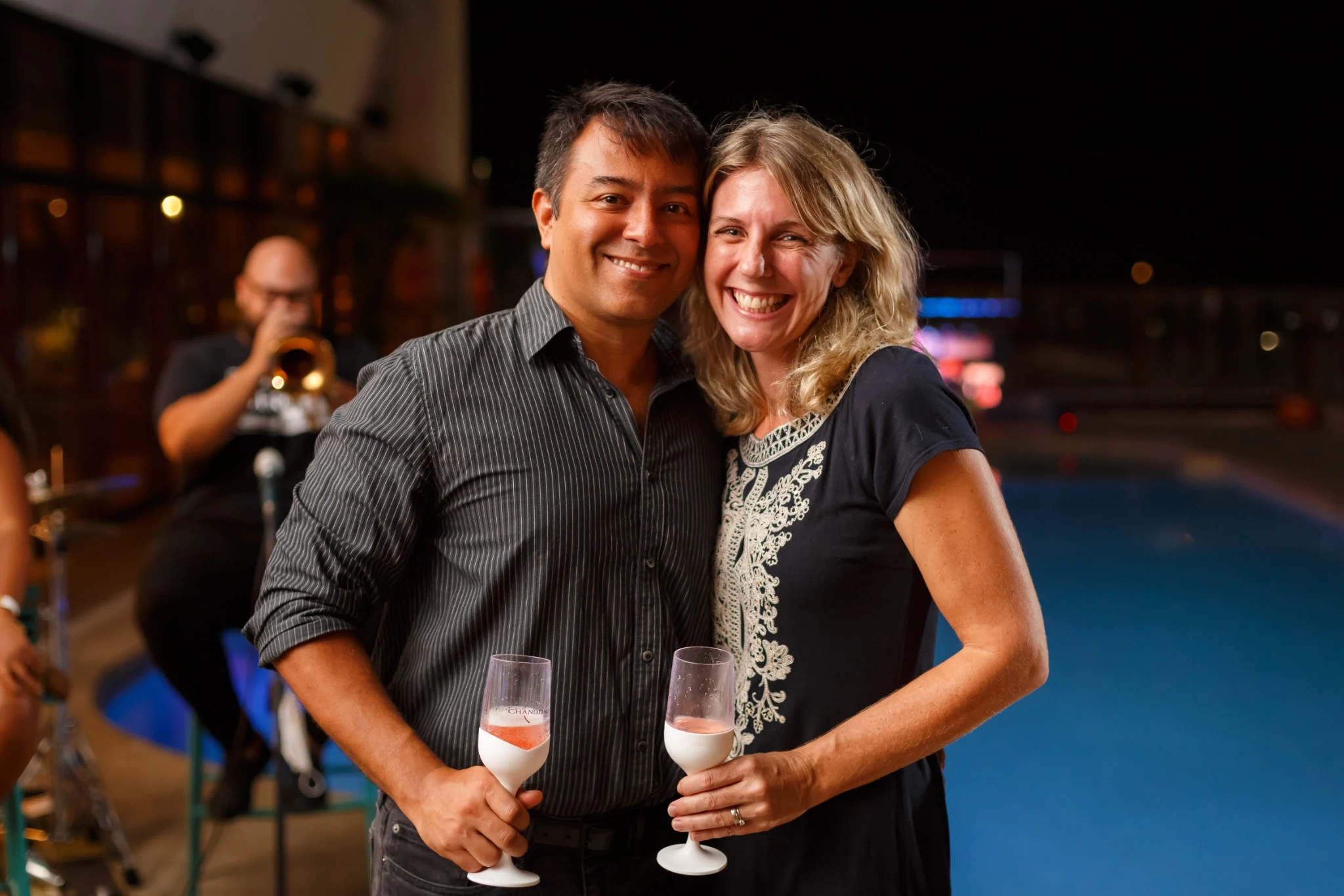 Two guests holding drinks beside the pool at a Hilton reception.